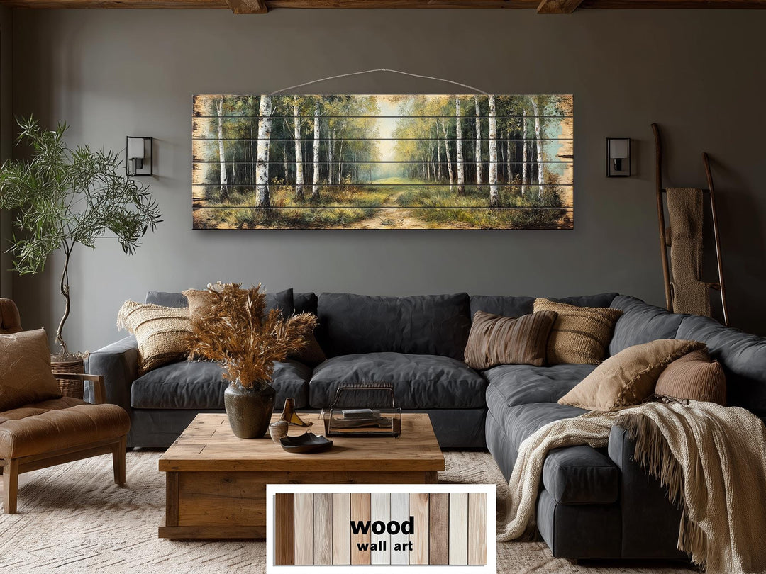 A panoramic birch forest scene printed on rustic wood planks hangs above a dark gray sectional sofa.