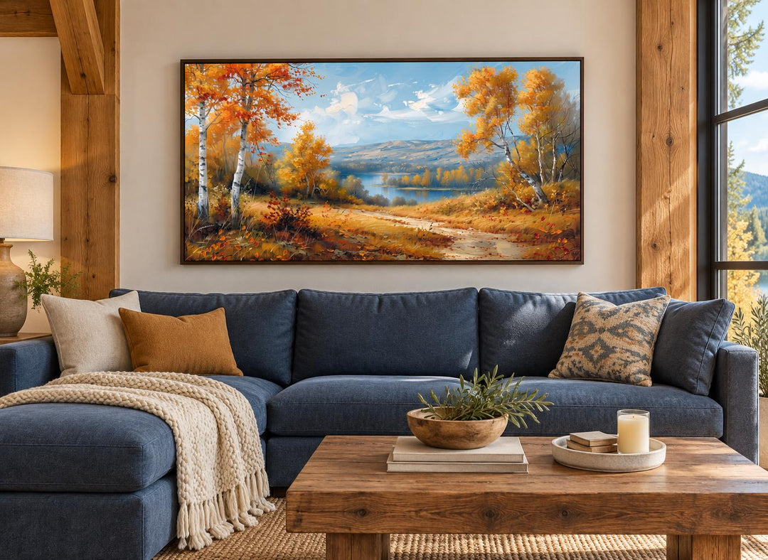 Birch Trees Forest and River in Autumn framed canvas wall art hanging above a blue sectional sofa.