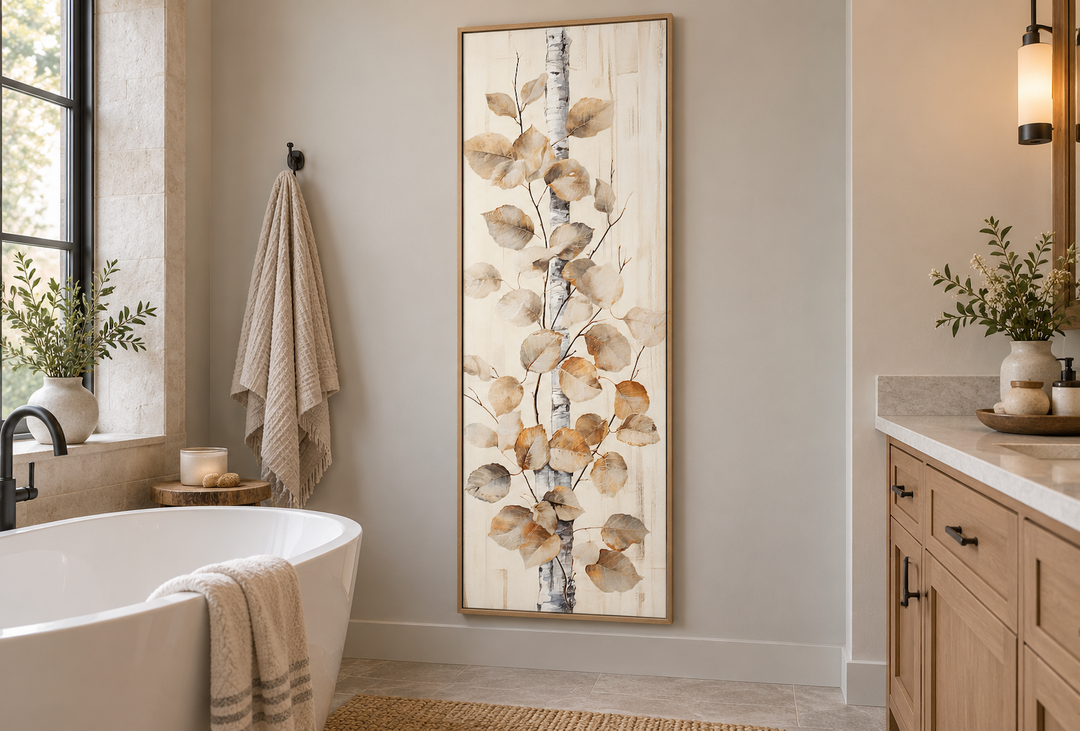 Tall narrow framed canvas wall art of a birch tree branch with leaves in a rustic bathroom.