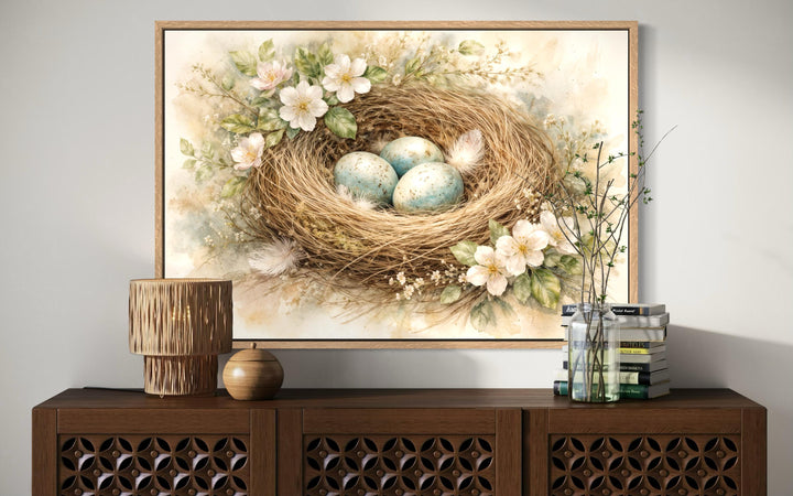 Bird nest wall art canvas print with blue eggs and pastel florals displayed above a wooden console.
