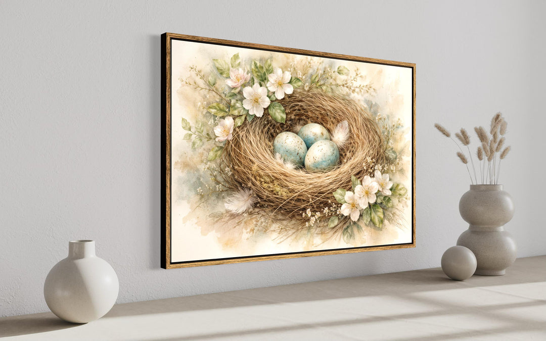 Bird nest wall art canvas print with blue eggs and pastel florals in a thin wood frame.