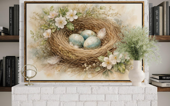 A framed canvas print of a bird's nest with blue eggs and spring flowers above a white fireplace.