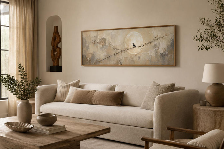 Bird on branch silhouette with moon neutral beige abstract canvas print above a beige sofa.