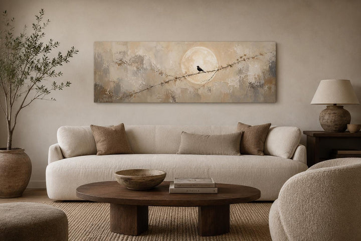 Bird on branch silhouette with moon neutral beige abstract canvas print above a cream sofa.