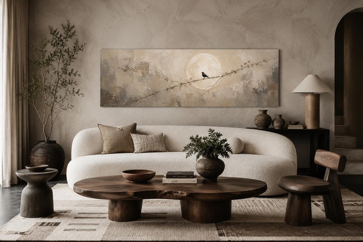 Bird on branch silhouette with moon neutral beige abstract canvas print above a white sofa.