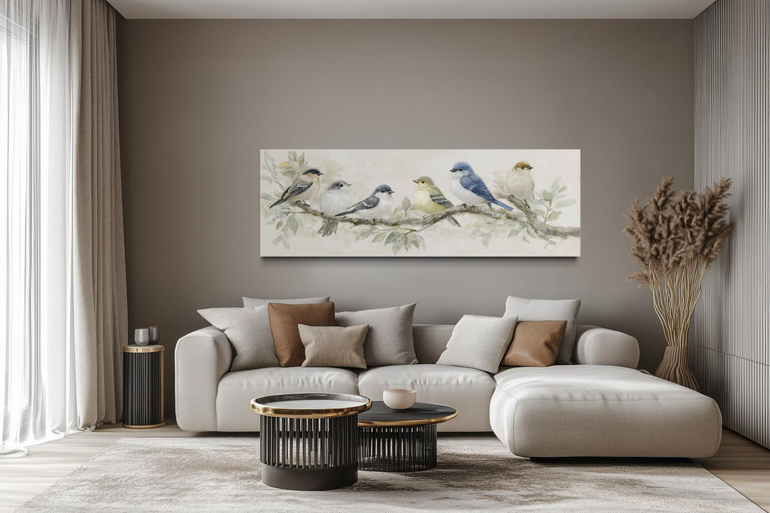 Panoramic canvas print of birds on a branch in neutral tones hanging above a modern sofa.