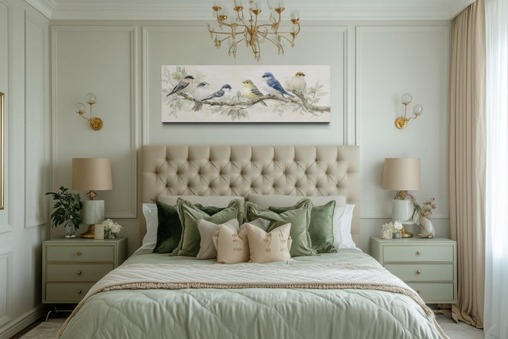 Panoramic canvas print of birds on a branch in neutral tones hanging above a tufted headboard.