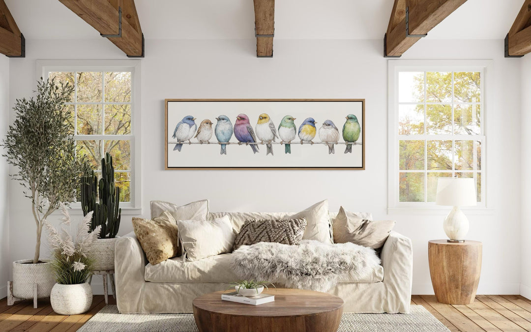 A long horizontal framed canvas of colorful songbirds on a wire in a modern farmhouse living room.