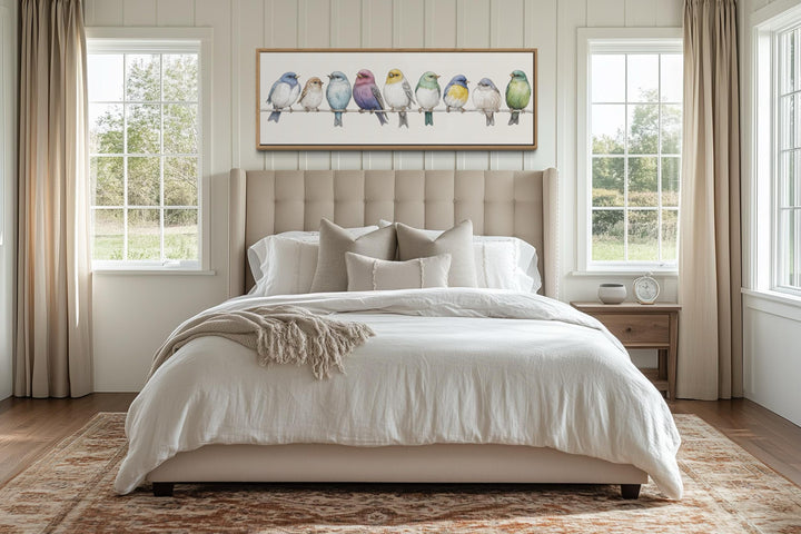 A framed canvas of colorful songbirds on a wire hangs above a bed in a modern farmhouse bedroom.