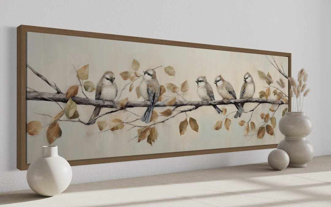 Panoramic framed canvas wall art of five birds perched on a branch with earthy-toned leaves.