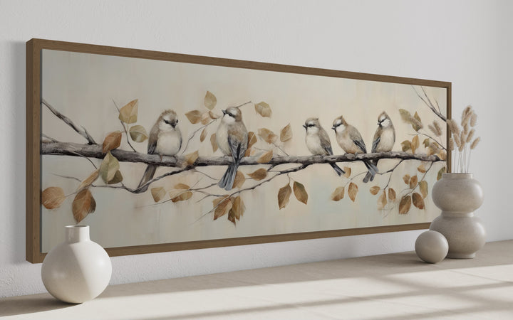 Panoramic framed canvas wall art of five birds perched on a branch with earthy-toned leaves.