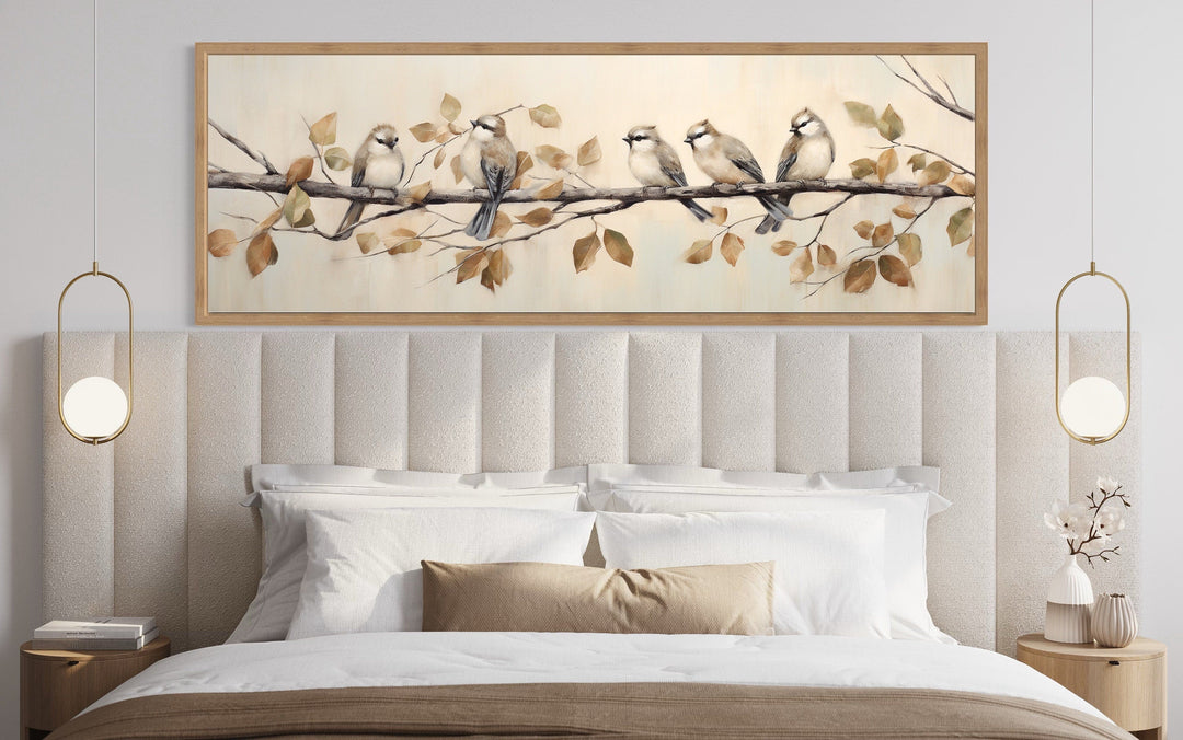 Panoramic framed canvas wall art of five birds perched on a branch above a bed.