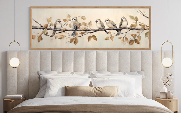 Panoramic framed canvas wall art of five birds perched on a branch above a bed.