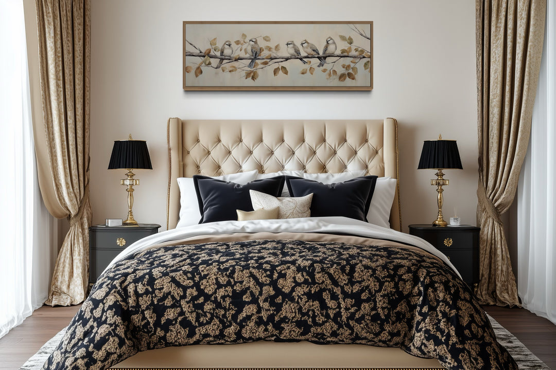 Panoramic framed canvas wall art of birds on a branch above a tufted headboard in a bedroom.