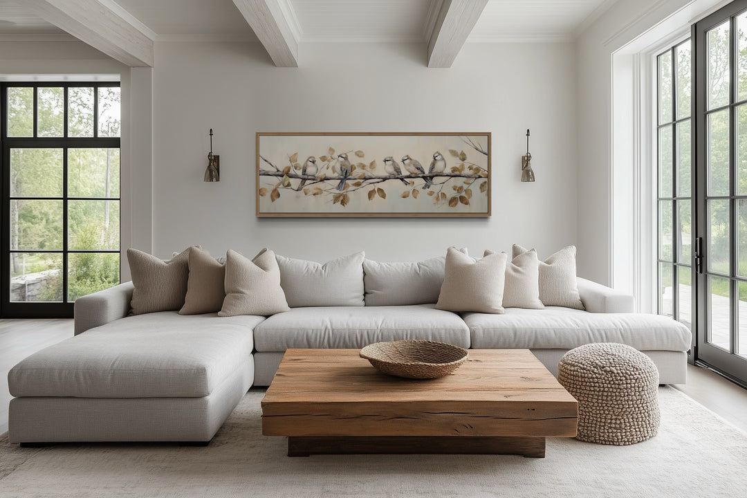 Panoramic framed canvas wall art of birds perched on a branch above a modern sectional sofa.