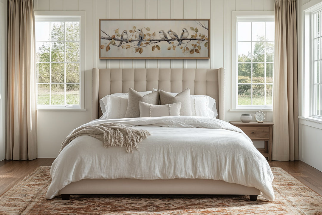 Panoramic framed canvas wall art of birds on a branch above a bed in a farmhouse-style bedroom.
