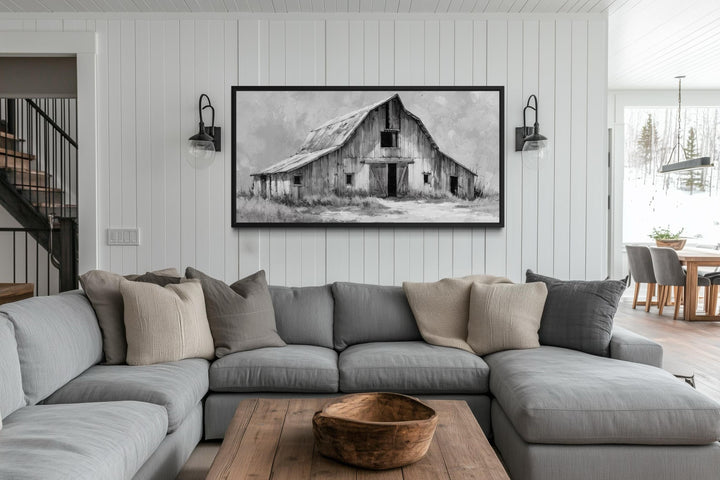 A rustic black and white barn canvas print hangs above a gray sectional in a farmhouse living room.
