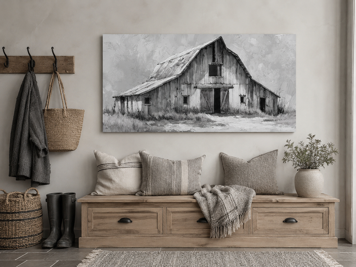Black and white barn canvas print hanging above a rustic wooden bench with pillows and a throw.