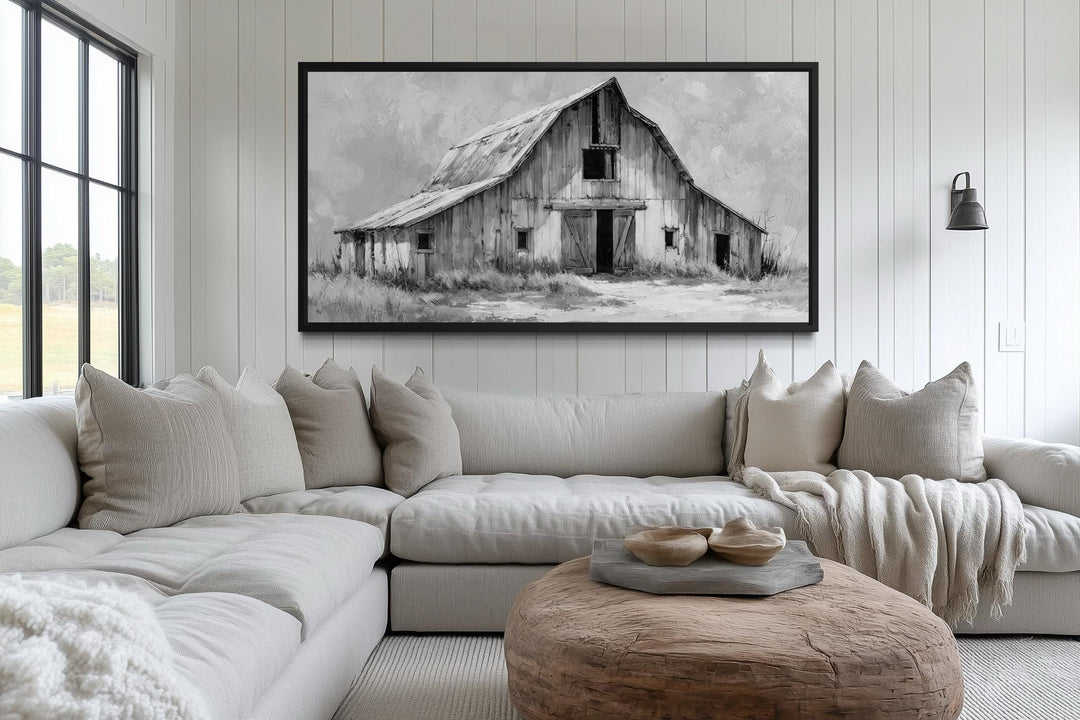 Black and white rustic barn canvas wall art hanging above a neutral-toned sectional sofa.