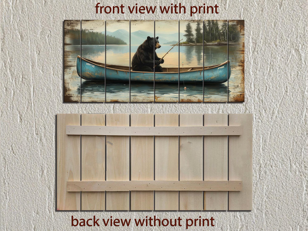 A rustic wood wall art piece featuring a black bear fishing in a blue canoe on a misty lake.