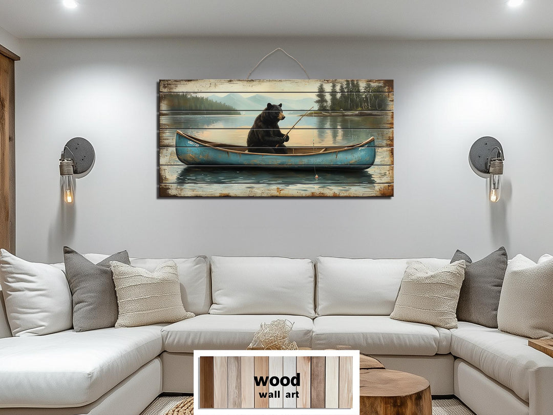 Horizontal wood wall art featuring a black bear fishing in a blue canoe above a white sectional sofa.
