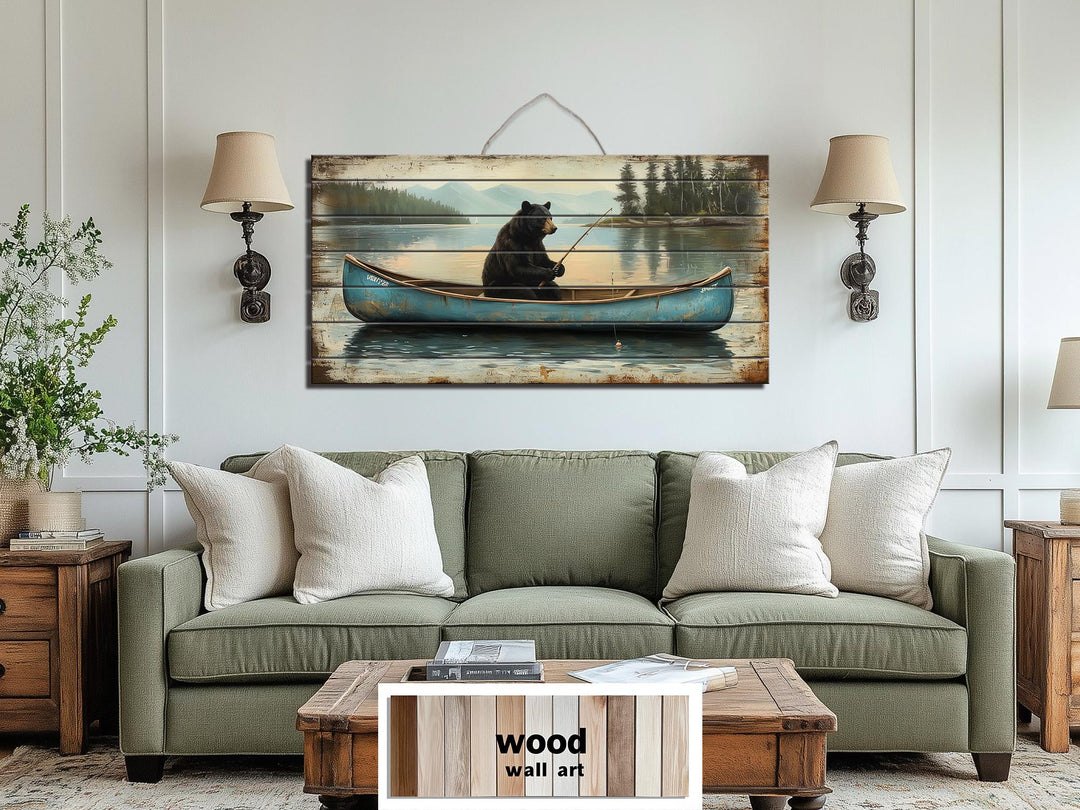 Rustic wood wall art featuring a black bear fishing in a blue canoe over a green sofa.