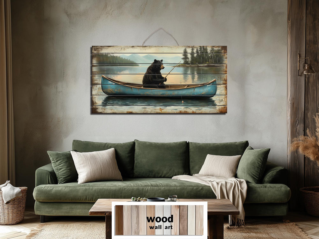 Rustic wood wall art featuring a black bear fishing in a blue canoe above a green sofa.