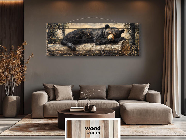 Horizontal wood wall art of a black bear sleeping on a log, hung above a modern brown sofa.