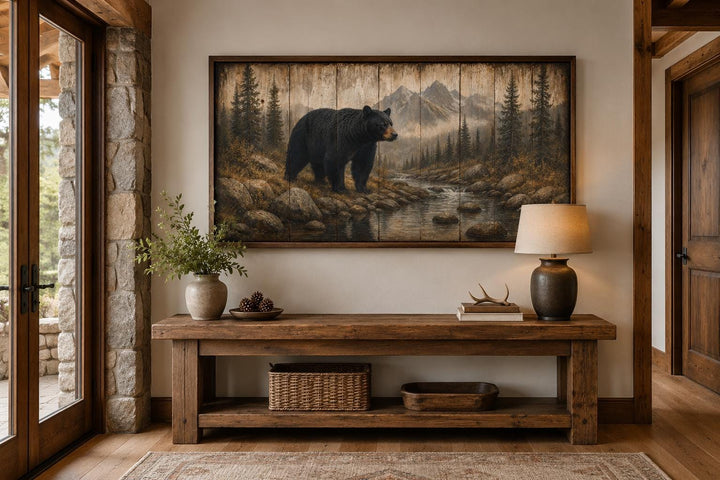 Rustic black bear canvas print in a mountain forest scene, framed above a wooden console table.