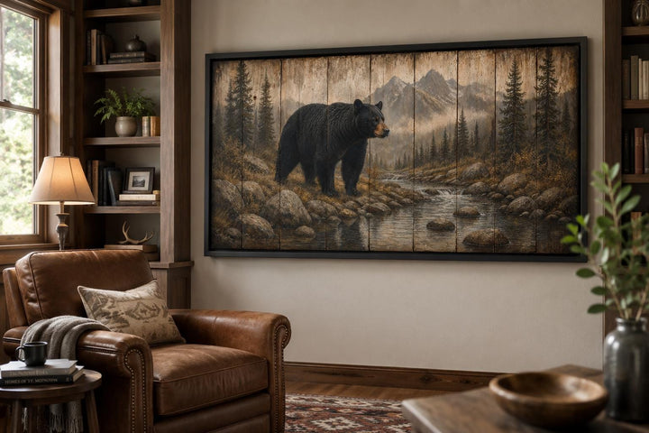 Rustic black bear canvas print in a mountain lodge setting with leather chair and wood bookshelves.
