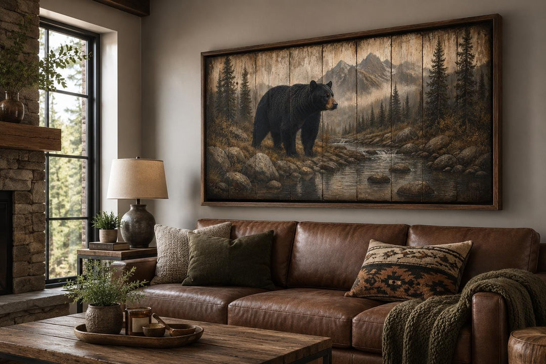 Rustic black bear canvas print on wood panels above a leather sofa in a mountain lodge living room.