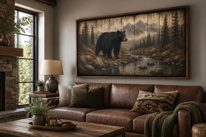 Rustic black bear canvas print on wood panels above a leather sofa in a mountain lodge living room.