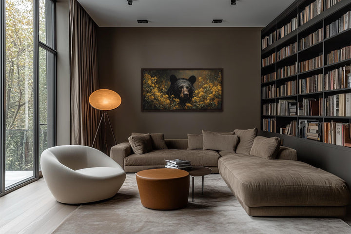 Black bear in yellow wildflowers canvas wall art hanging in a modern living room with a brown sofa.
