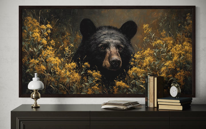 Black bear canvas wall art featuring a bear in golden wildflowers, framed above a dark console.