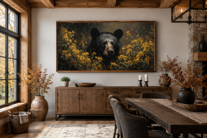 Black bear in yellow wildflowers canvas wall art hanging above a wooden sideboard in a rustic room.