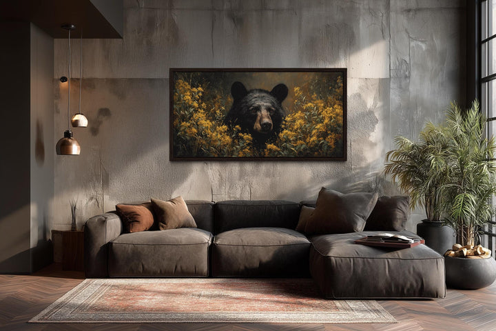 Black bear in yellow wildflowers canvas wall art hanging above a modern sofa in a rustic room.