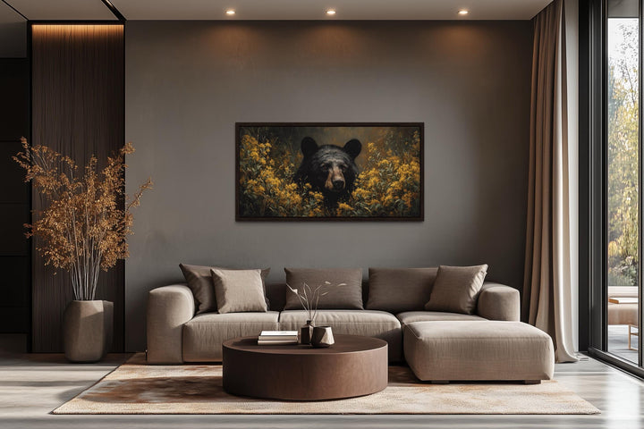 Black bear in yellow wildflowers canvas wall art hanging above a modern sofa in a living room.
