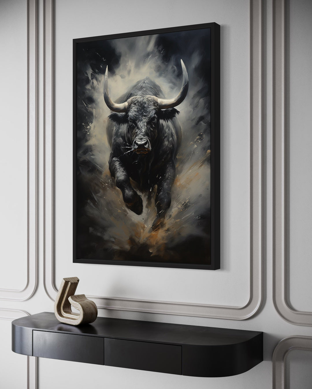 Black charging bull abstract framed canvas wall art on a white paneled wall above a black console.