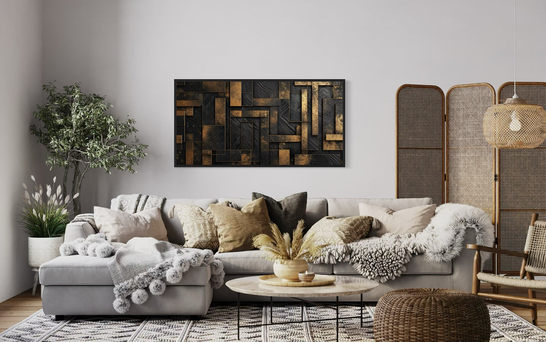 Black and gold abstract geometric framed canvas wall art hanging above a sofa in a living room.