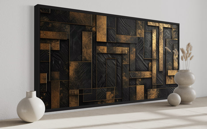 Black and gold abstract geometric framed canvas wall art displayed on a white wall.