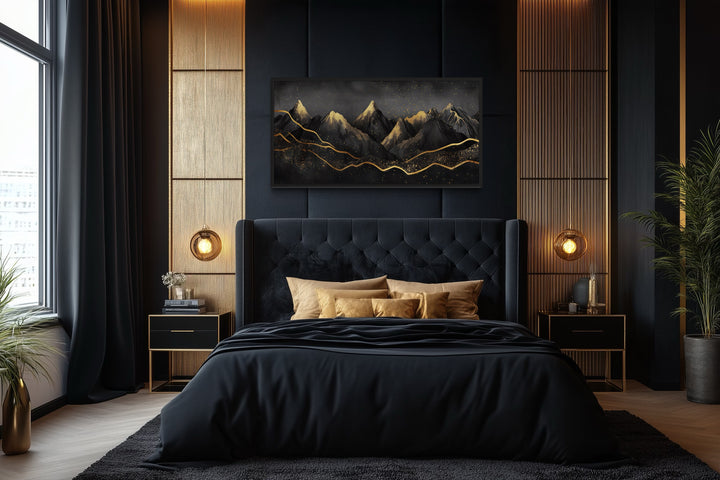 Black and gold abstract mountain framed canvas wall art hanging above a black tufted bed.