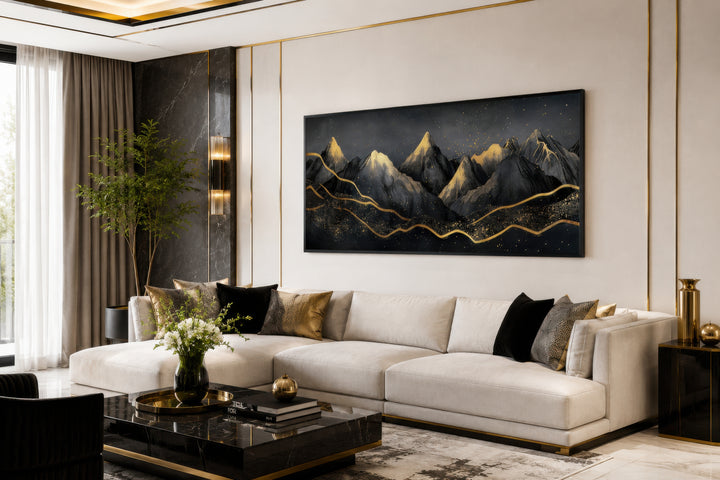 Black gold abstract mountain framed canvas wall art hanging above a white sectional sofa.
