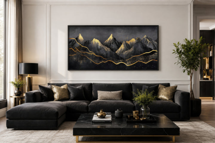 Black and gold abstract mountain framed canvas wall art hanging above a dark grey sectional sofa.
