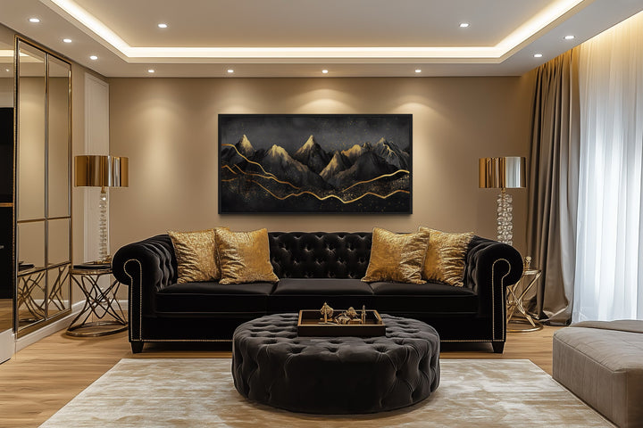 Black and gold abstract mountain framed canvas wall art hanging above a black velvet sofa.
