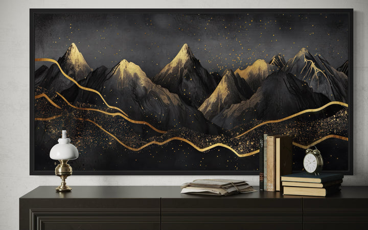 Black and gold abstract mountain framed canvas wall art displayed above a dark wooden sideboard.