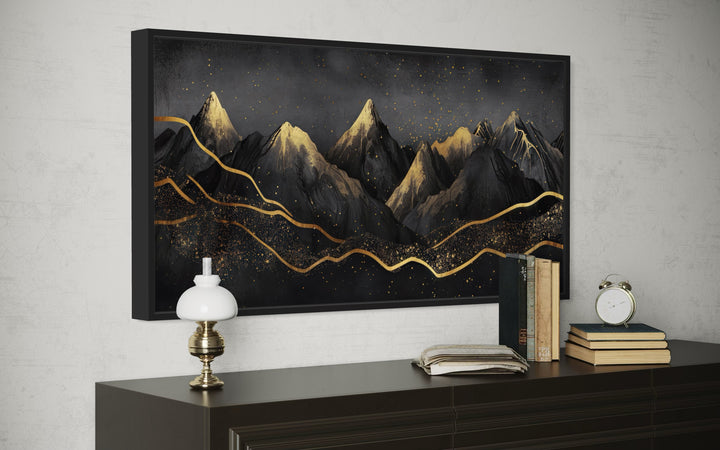 Black and gold abstract mountain framed canvas wall art hanging above a dark wood dresser.