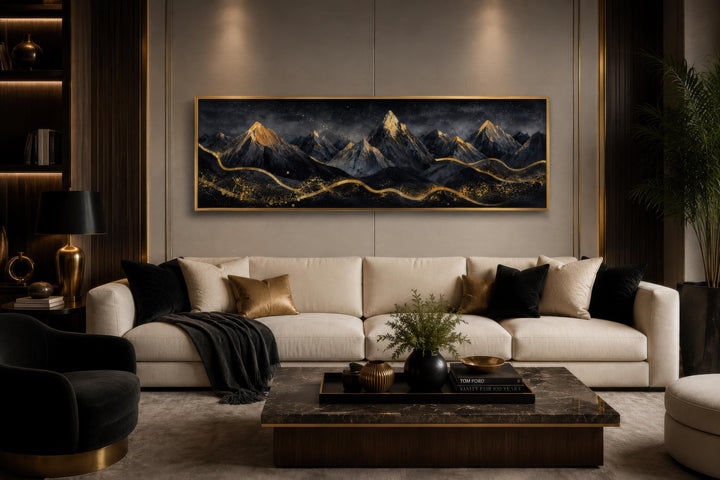 Long narrow canvas wall art of black and gold mountains hanging above a modern sofa in a living room.