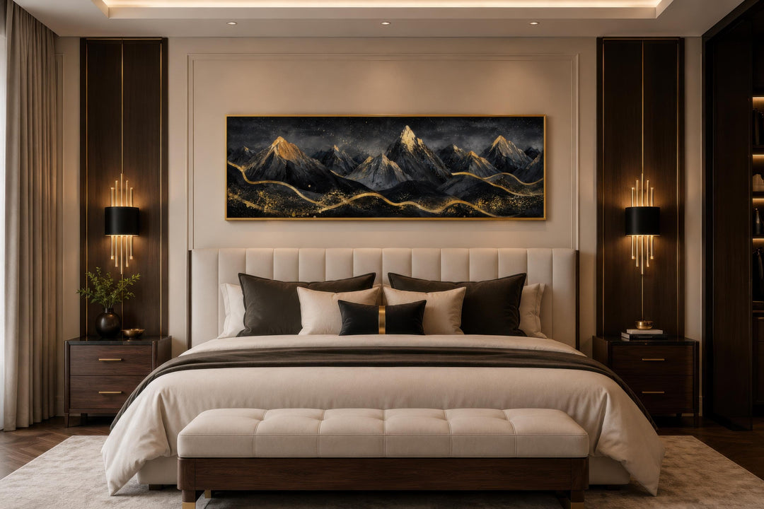 Long narrow canvas wall art featuring black and gold abstract mountains hanging above a bed.