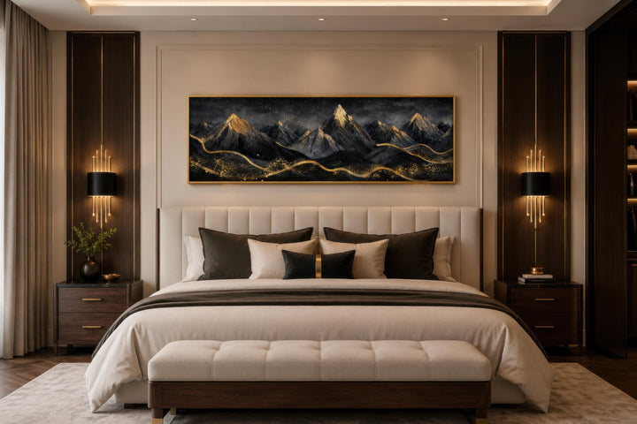 Long narrow canvas wall art featuring black and gold abstract mountains hanging above a bed.
