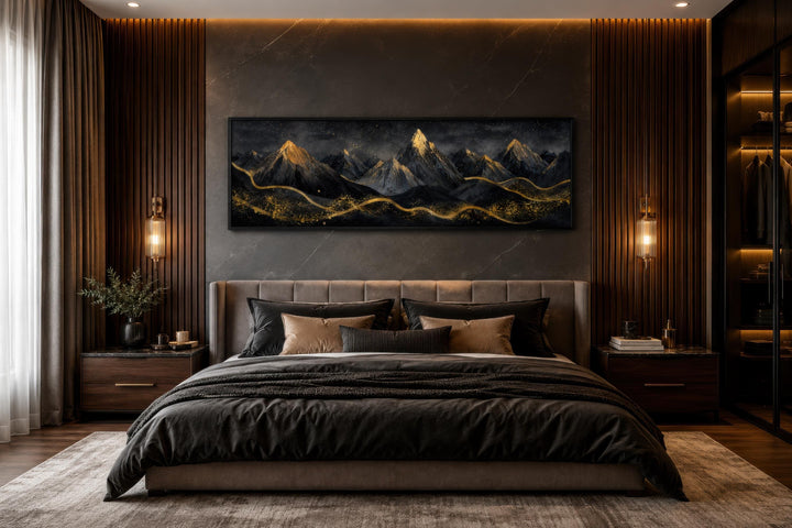 Long narrow canvas wall art featuring black and gold abstract mountains above a modern bed.